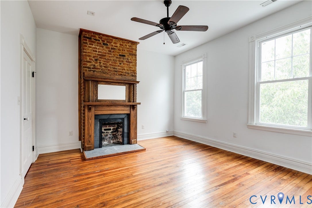 1416 Oakwood Avenue, Church Hill, Richmond, VA 23223 Hardwood flooring, exposed brick fireplace with wood mantel, two large windows, ceiling fan, and white trim