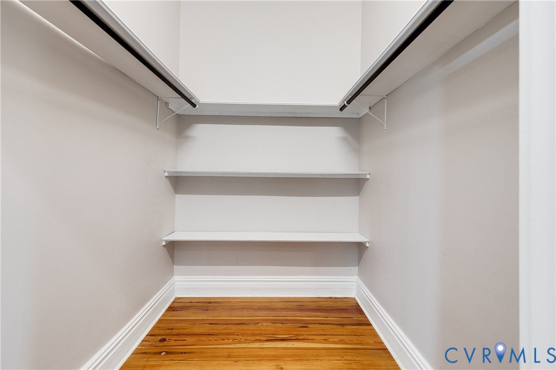 1416 Oakwood Avenue, Church Hill, Richmond, VA 23223 Wood-finish flooring with white baseboards, light neutral wall paint, and white shelving units with hanging rods