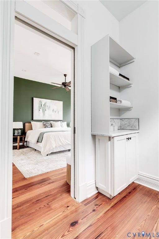 1416 Oakwood Avenue, Church Hill, Richmond, VA 23223 Hardwood flooring, painted white baseboards, built-in white cabinetry with closed storage, open shelving, and a ceiling fan