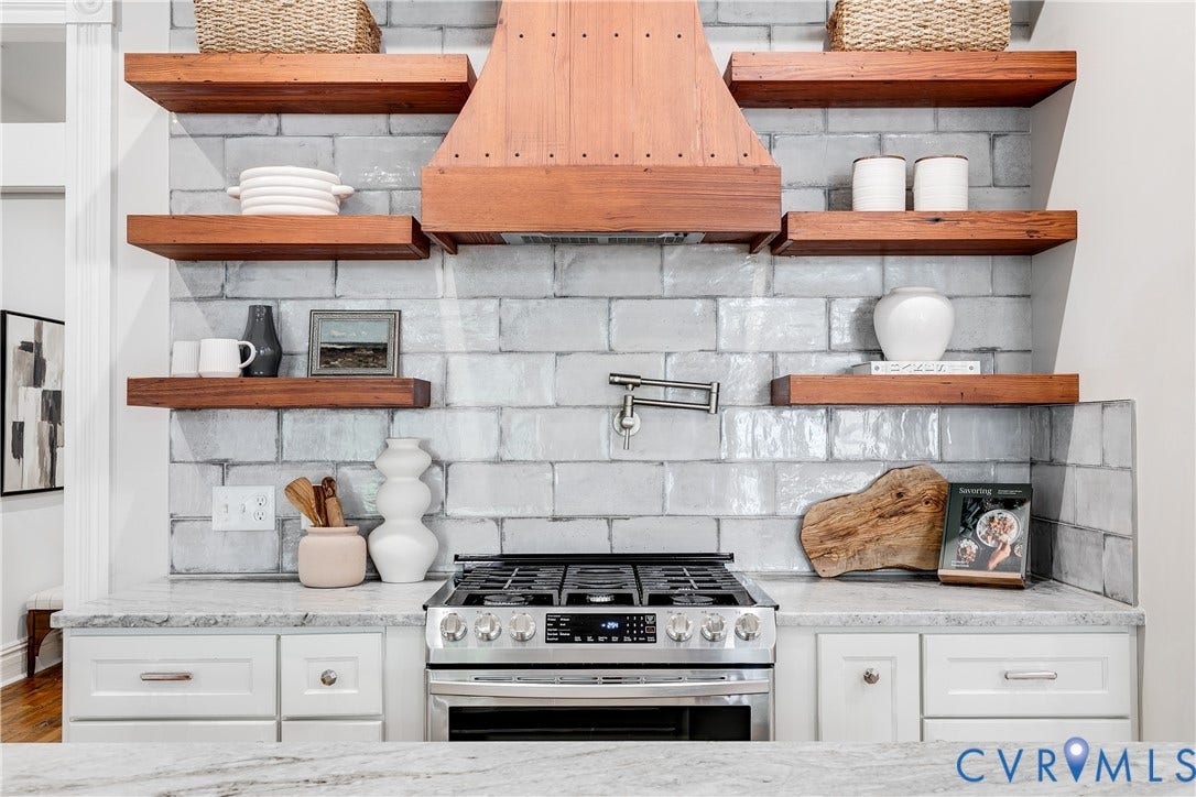 1416 Oakwood Avenue, Church Hill, Richmond, VA 23223 Stainless steel range with a pot filler, light-toned subway tile backsplash, wood-toned floating shelves, wood-toned range hood, and light-toned countertops