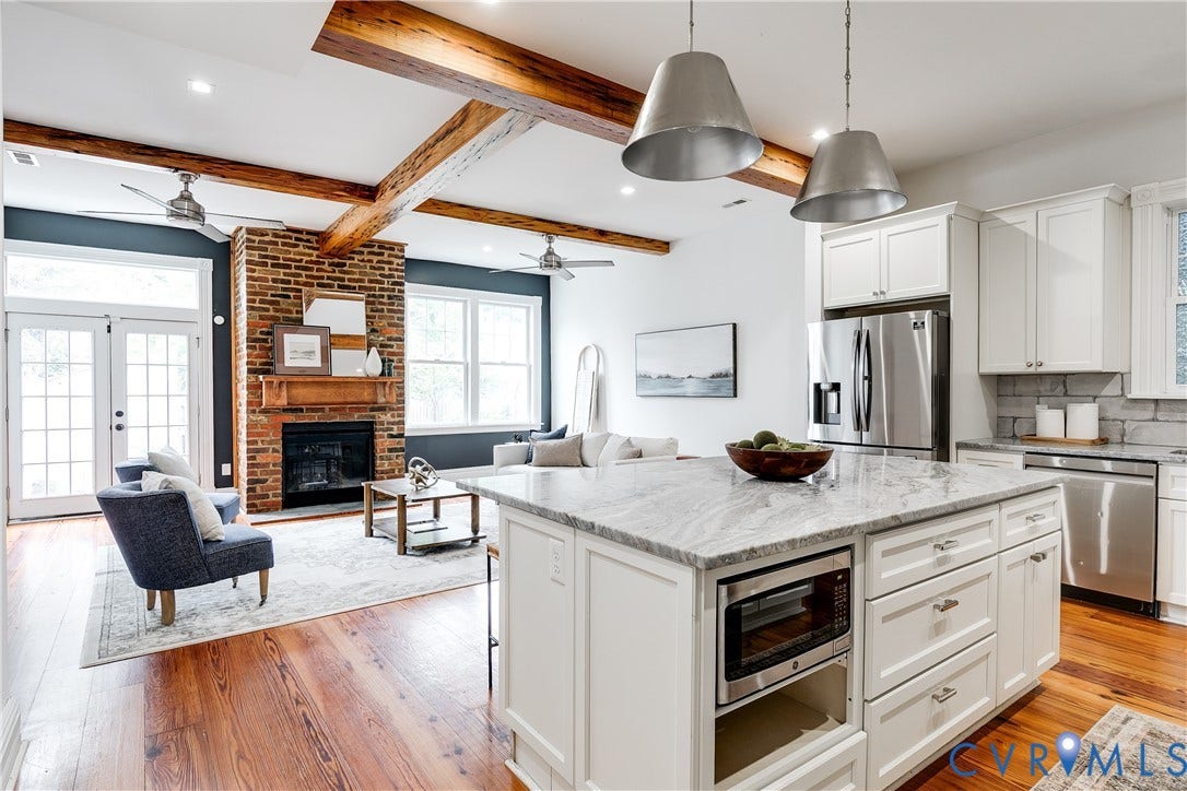 1416 Oakwood Avenue, Church Hill, Richmond, VA 23223 Hardwood flooring throughout, exposed wood ceiling beams, white cabinetry, integrated stainless steel appliances, and a brick fireplace