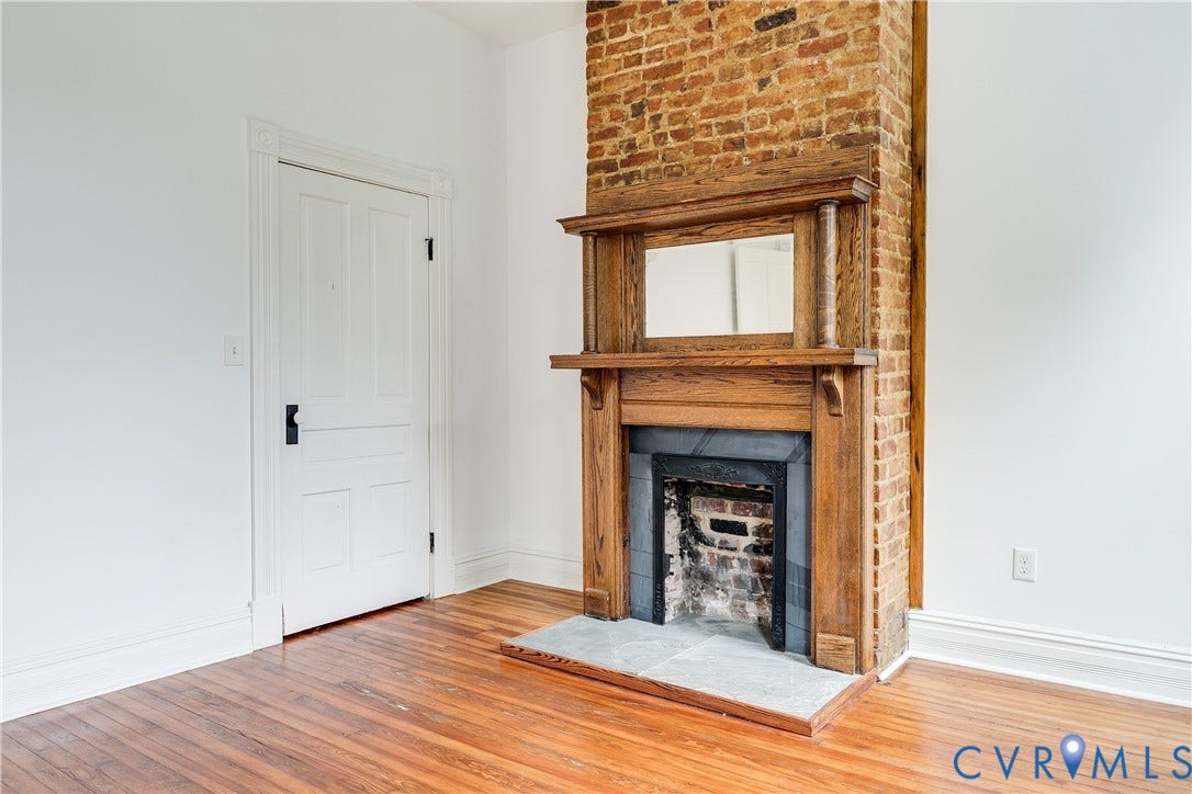 1416 Oakwood Avenue, Church Hill, Richmond, VA 23223 Exposed brick chimney, wood-finish flooring, wood mantelpiece, hearth with stone tile, and a paneled door with decorative trim