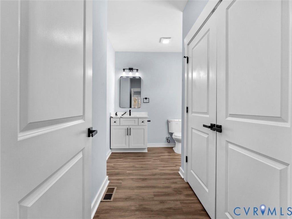 2719 General Boulevard, Chesterfield, VA 23237 Bathroom featuring wood-finish flooring, a contemporary vanity with a rectangular basin, a wall-mounted mirror, and a modern light fixture