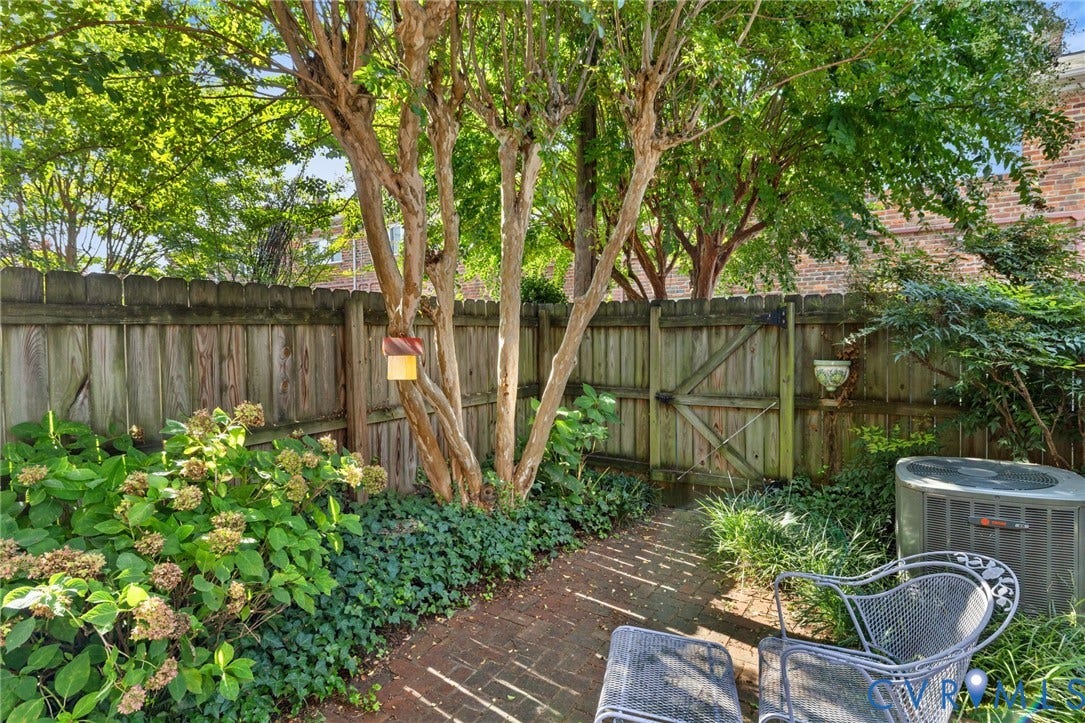505 N Hamilton Street, #F, Richmond, VA 23221 Brick pathway bordered by mature trees and lush landscaping, featuring a wooden privacy fence with a gate