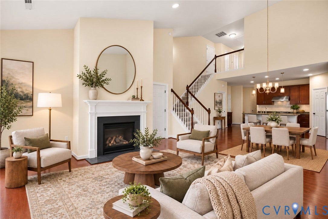 508 Winterhawk Place, Glen Allen, VA 23059 Open-concept living space featuring a fireplace with a classic mantel, wood-finish flooring, a two-story ceiling, and a kitchen with dark wood cabinetry and stainless steel appliances. Photo virtually staged