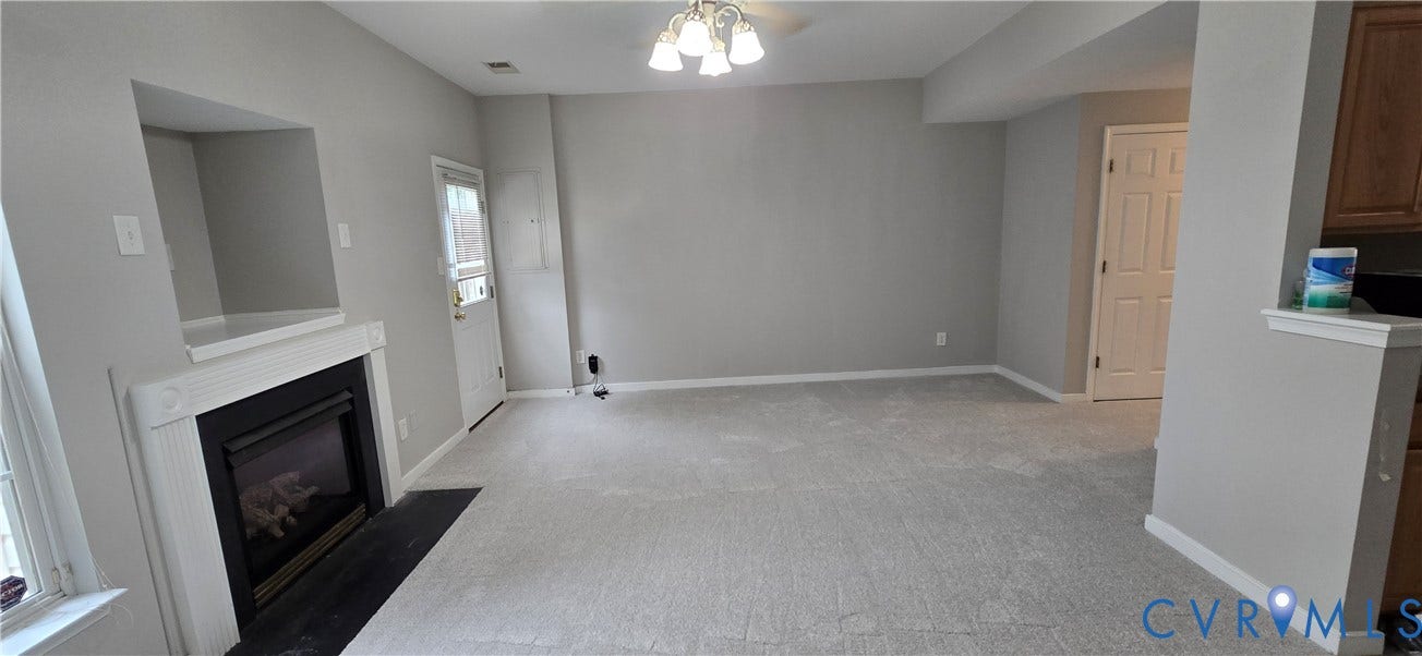 5506 Millwheel Lane, Henrico, VA 23228 Recessed fireplace with mantel and hearth, carpeted flooring, overhead ceiling light fixture, white trim, and a paneled door