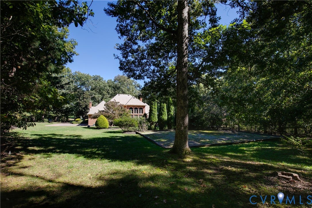 2621 Glenalmond Court, Powhatan, VA 23139 Expansive green lawn with mature trees and a brick-faced exterior featuring arched windows
