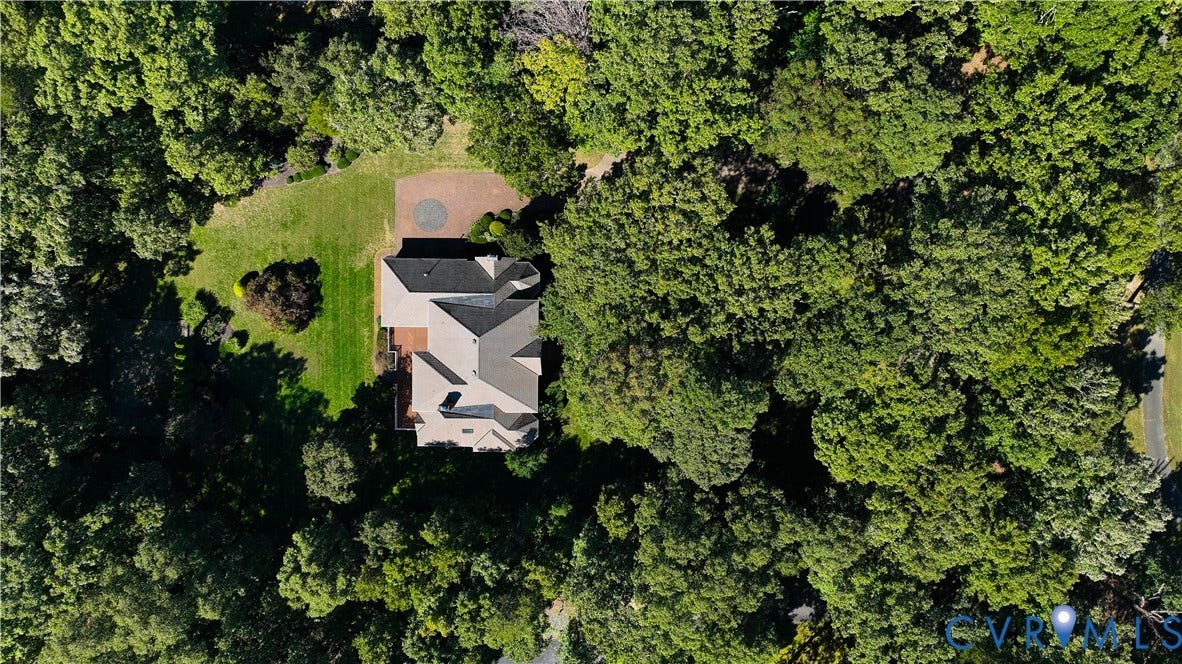 2621 Glenalmond Court, Powhatan, VA 23139 Property surrounded by mature trees, featuring a gabled roofline, a rear deck, a manicured lawn, and a circular brick paver patio