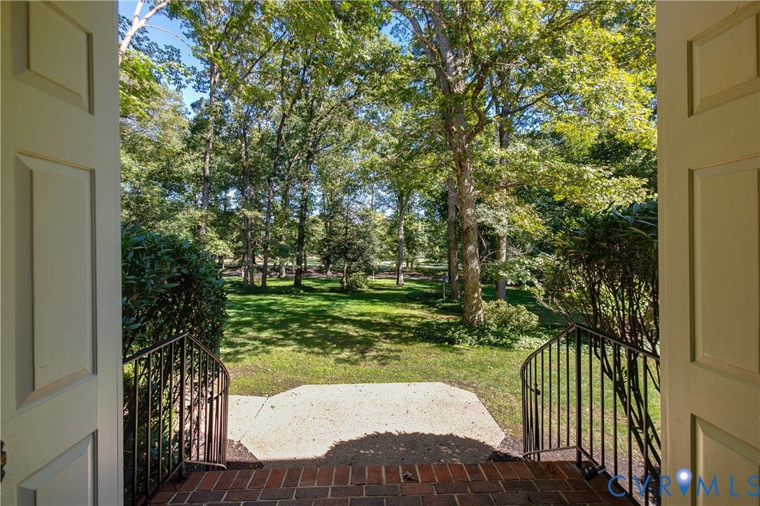 2621 Glenalmond Court, Powhatan, VA 23139 Brick steps leading to a concrete landing, flanked by wrought iron railings and lush greenery, opening to a verdant landscape with mature trees
