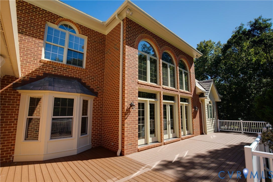2621 Glenalmond Court, Powhatan, VA 23139 Expansive composite deck with white railing, brick exterior, multiple arched windows, double French doors, and a bay window with a shingled roof