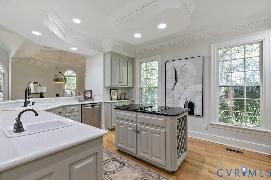 2621 Glenalmond Court, Powhatan, VA 23139 Light-toned cabinetry with white countertops, a central island with a dark countertop and integrated wine storage, stainless steel appliances, and wood-finish flooring