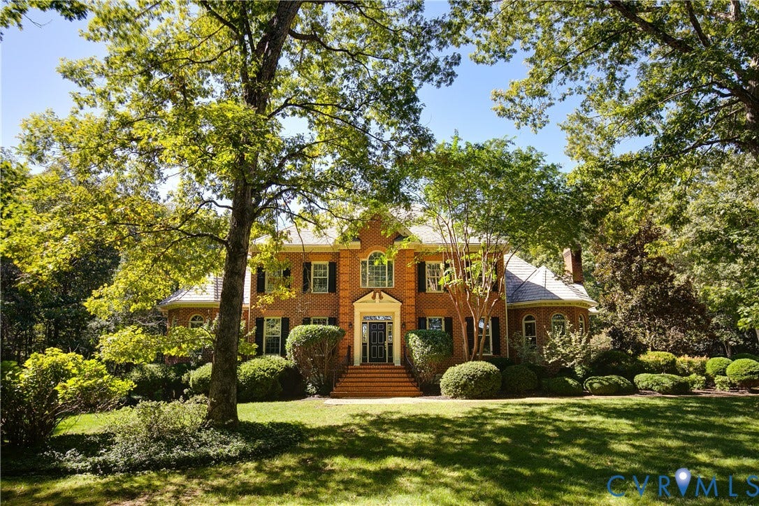 2621 Glenalmond Court, Powhatan, VA 23139 Brick colonial-style residence featuring a prominent front entrance with a portico, symmetrical windows with dark shutters, a curved bay window, and a green lawn