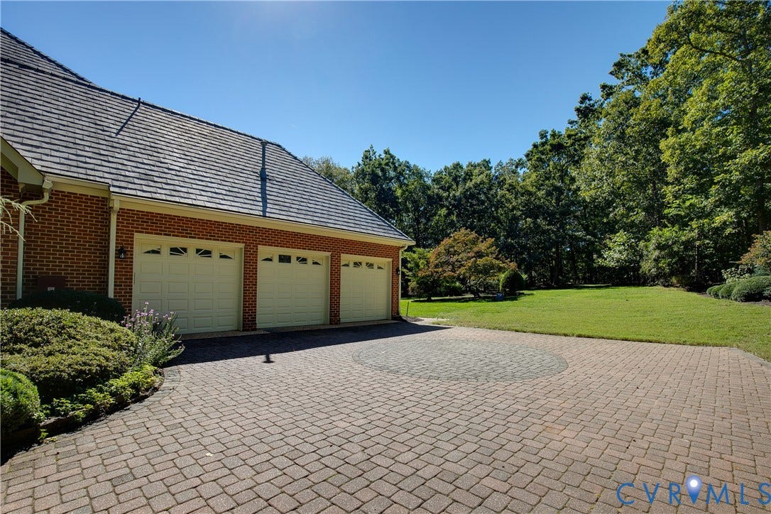 2621 Glenalmond Court, Powhatan, VA 23139 Brick exterior with a three-car garage, shingle roof, paver driveway, and landscaped perimeter