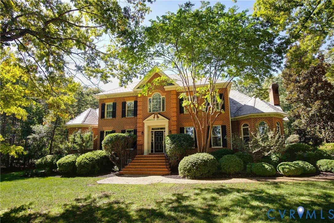 2621 Glenalmond Court, Powhatan, VA 23139 Brick colonial-style residence featuring a prominent front entrance with a portico, symmetrical windows with dark shutters, and a sloped roofline