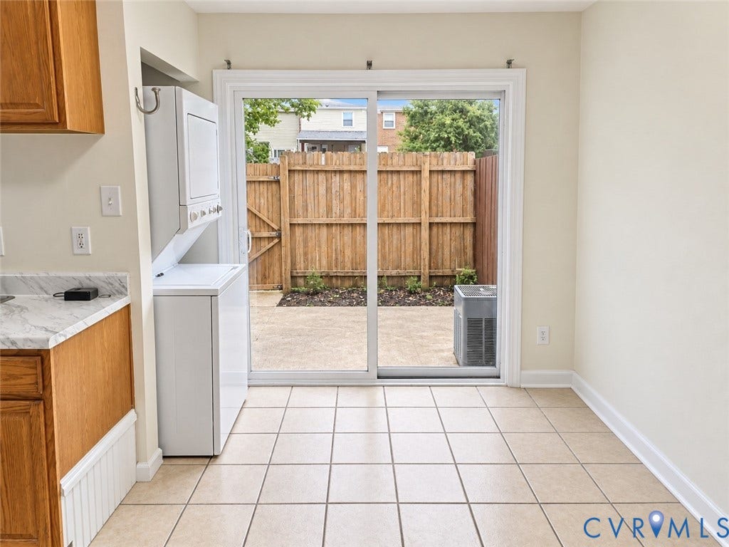 4609 Coldstream Drive, Richmond, VA 23234 Tiled flooring with sliding glass door access to a private patio featuring a wooden fence and stacked laundry appliances