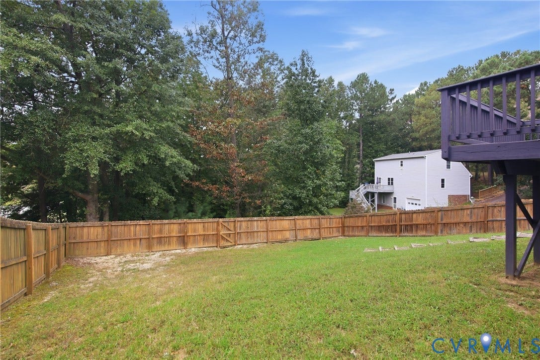 10624 Hamlin Drive, Hamlin Estates, Chester, VA 23831 Expansive backyard featuring a wood privacy fence with gate, large green lawn, mature trees, and a raised wooden deck