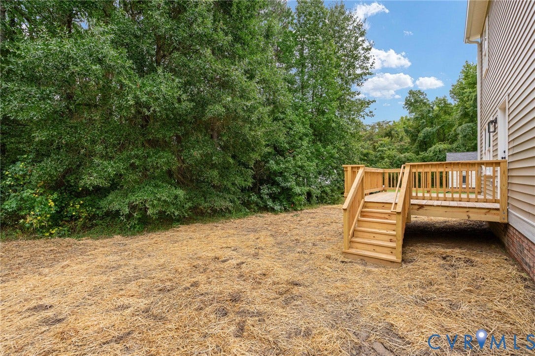 7603 Oster Drive, Chamberlayne Farms Area, Henrico, VA 23227 Rear wood-finish deck with railings and steps, set against a backdrop of mature trees