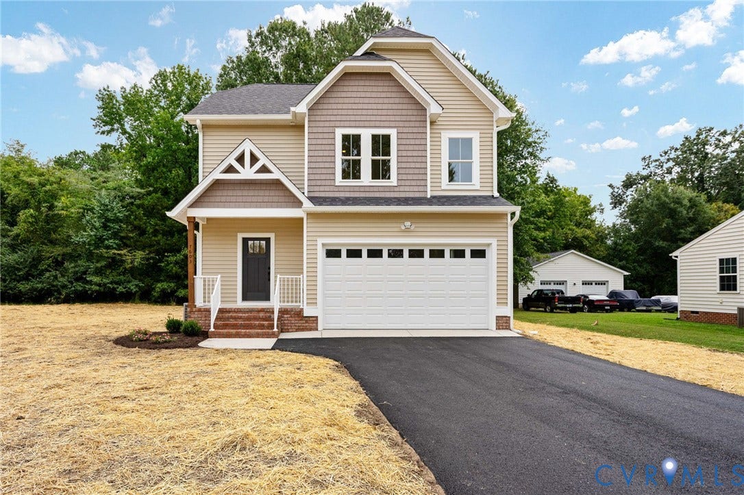 7603 Oster Drive, Chamberlayne Farms Area, Henrico, VA 23227 Two-story residence featuring light-colored siding, a covered front porch with white railings, an attached two-car garage, an asphalt driveway, and a partially visible outbuilding