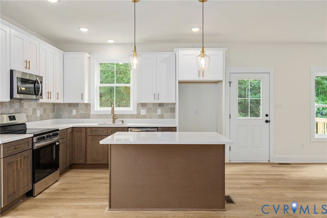 7603 Oster Drive, Chamberlayne Farms Area, Henrico, VA 23227 Wood-finish flooring throughout, two-tone cabinetry with white upper and brown lower cabinets, stainless steel appliances, a tiled backsplash, and an island with a white countertop