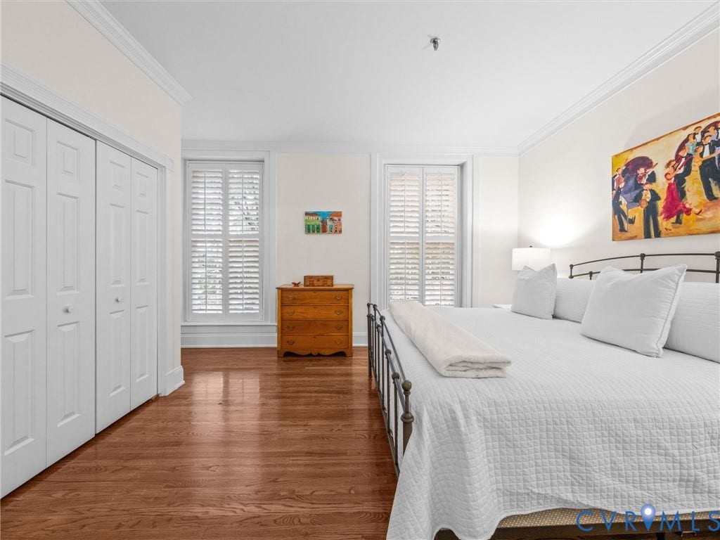 Hardwood flooring, crown molding, white bi-fold closet doors, two windows with plantation shutters, recessed lighting