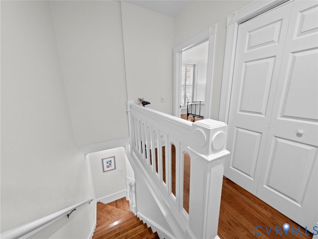 Hardwood flooring, painted white balusters, painted white handrail, recessed panel bifold doors, and decorative door trim