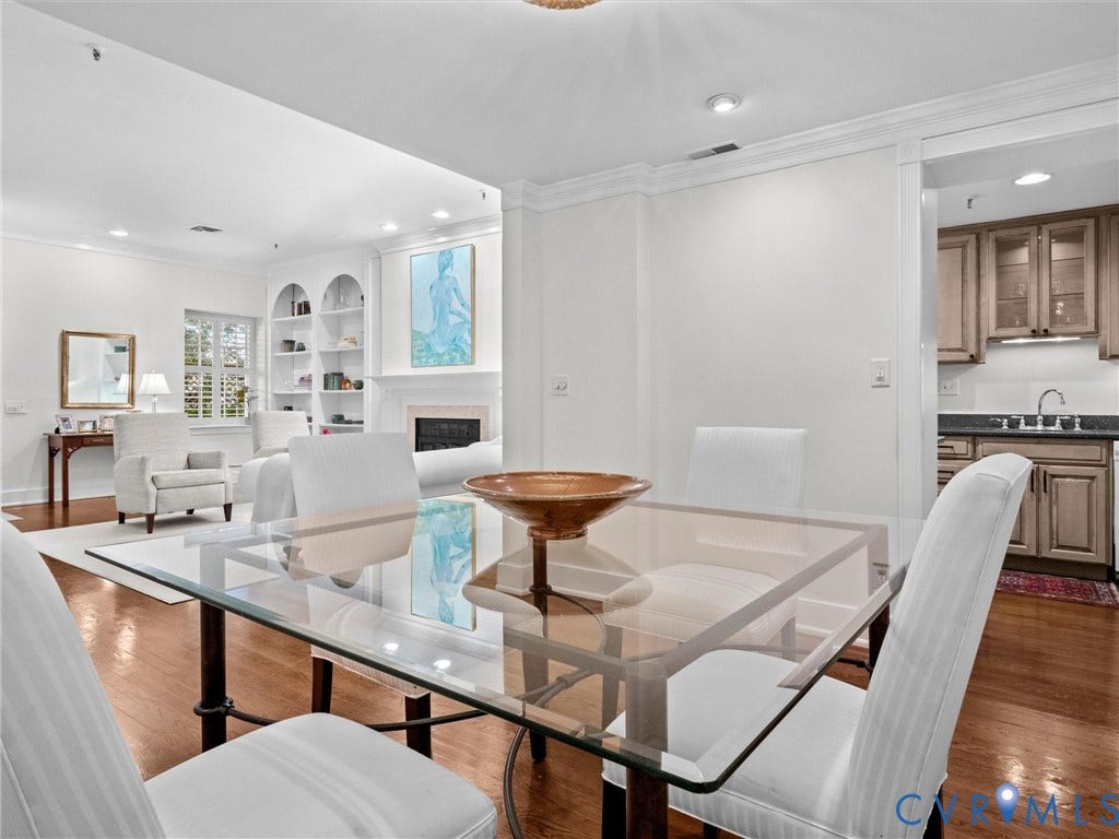 Hardwood flooring throughout, recessed lighting, crown molding, built-in shelving, and a fireplace with a stone surround