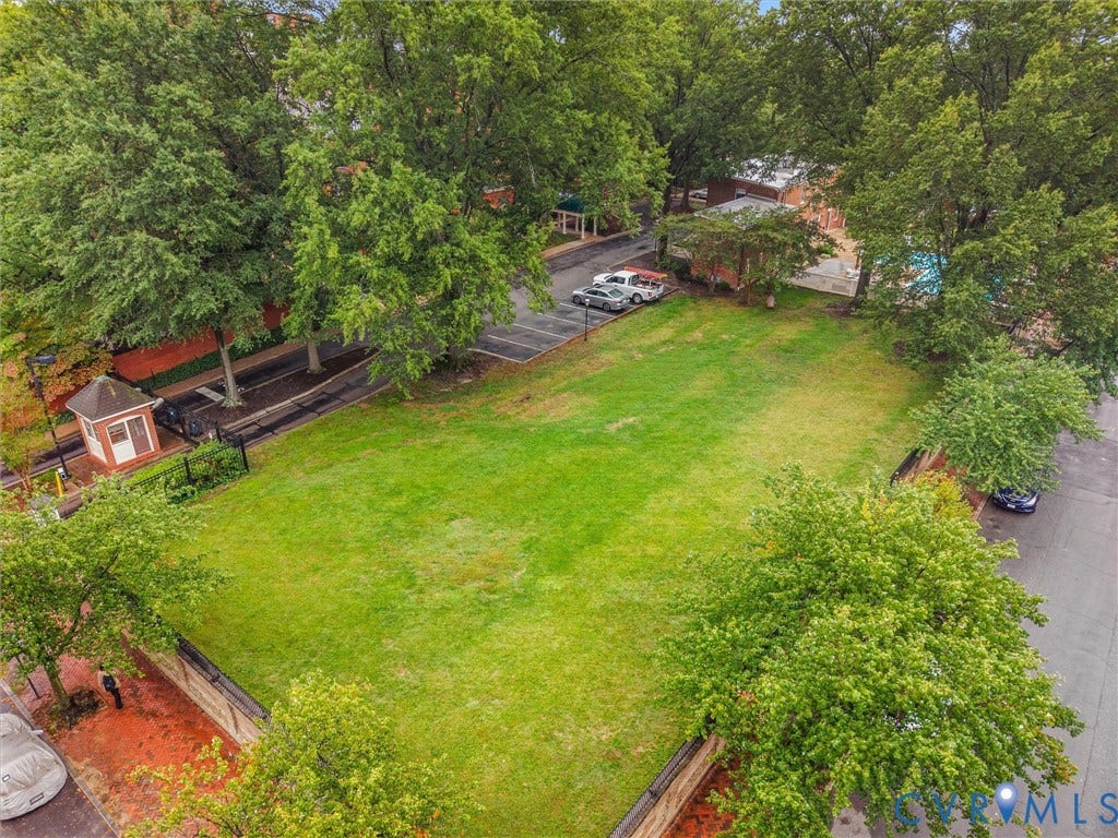 Expansive green space featuring mature trees and a paved parking area