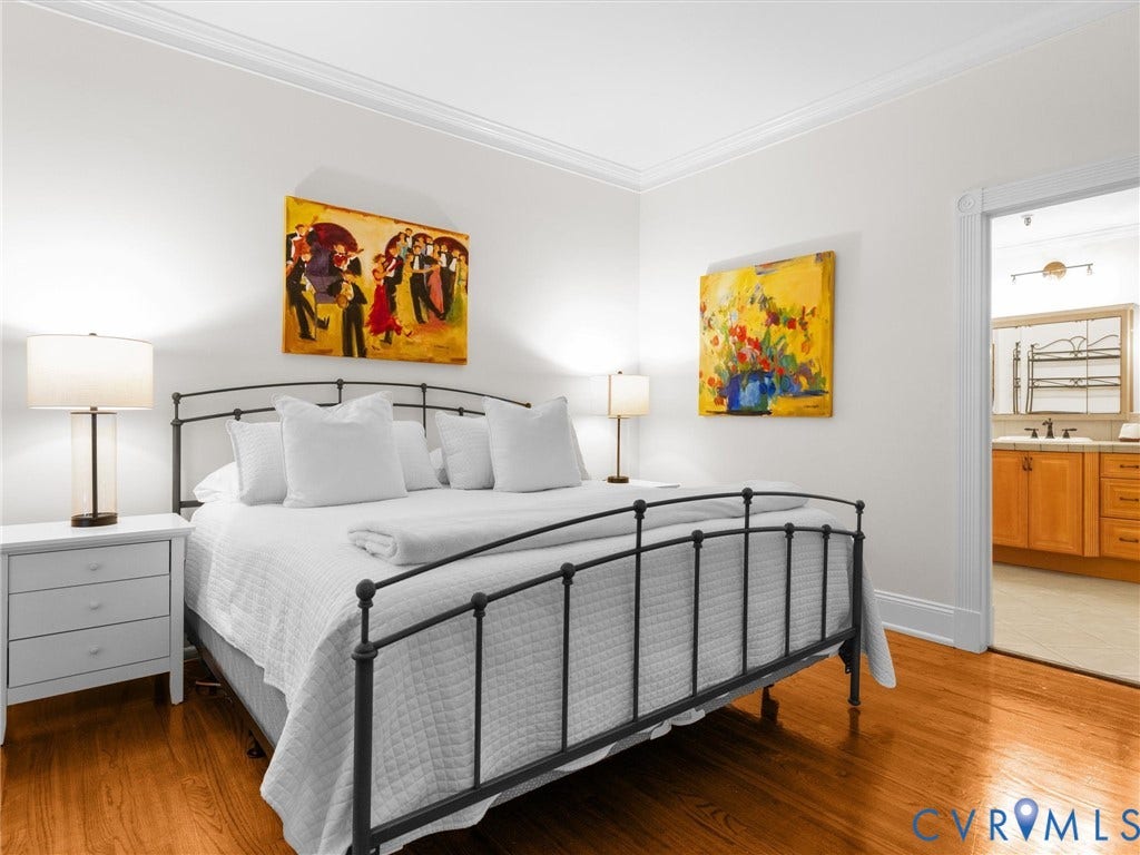 Hardwood flooring, crown molding, white walls, and an archway