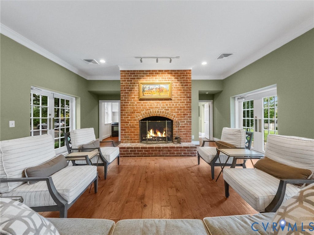 Brick fireplace with an arched hearth, wood-finish flooring, recessed lighting, and crown molding
