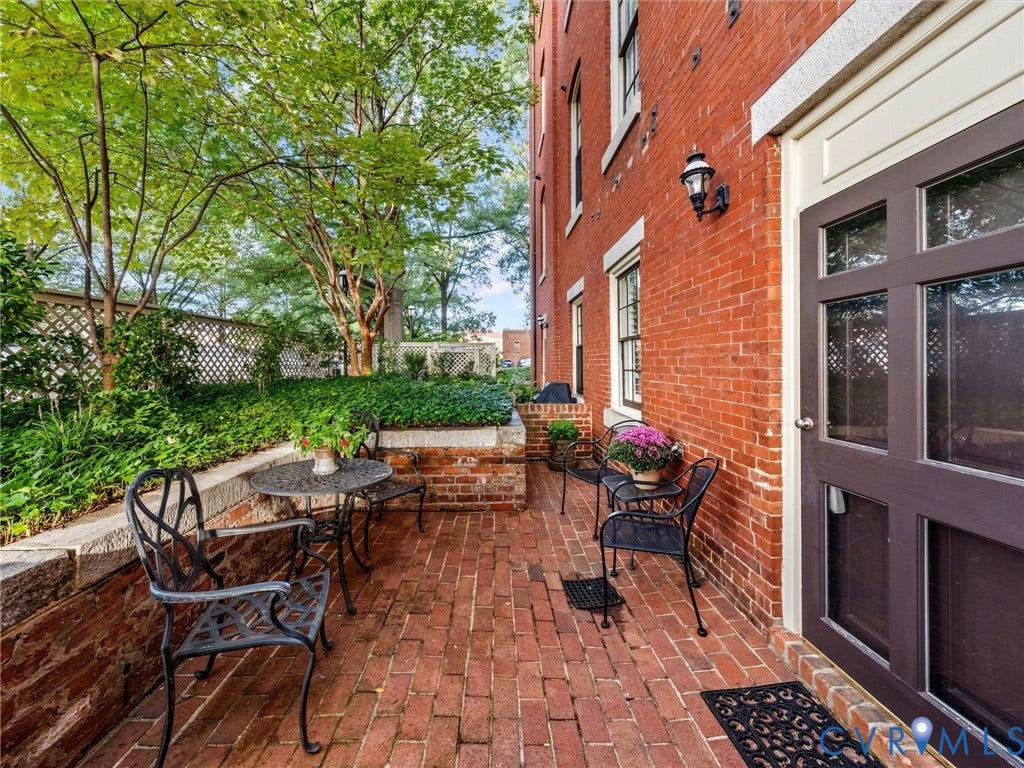 Brick patio area featuring a red brick facade, wood-framed windows, and decorative wall lighting
