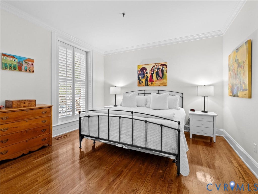 Hardwood flooring, plantation shutters, crown molding, and bright white wall finishes