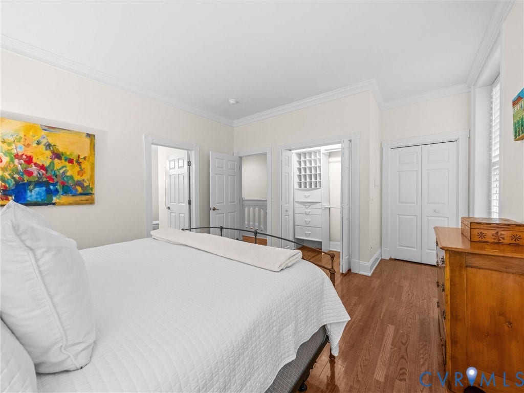 Wood-finish flooring, white walls, and crown molding