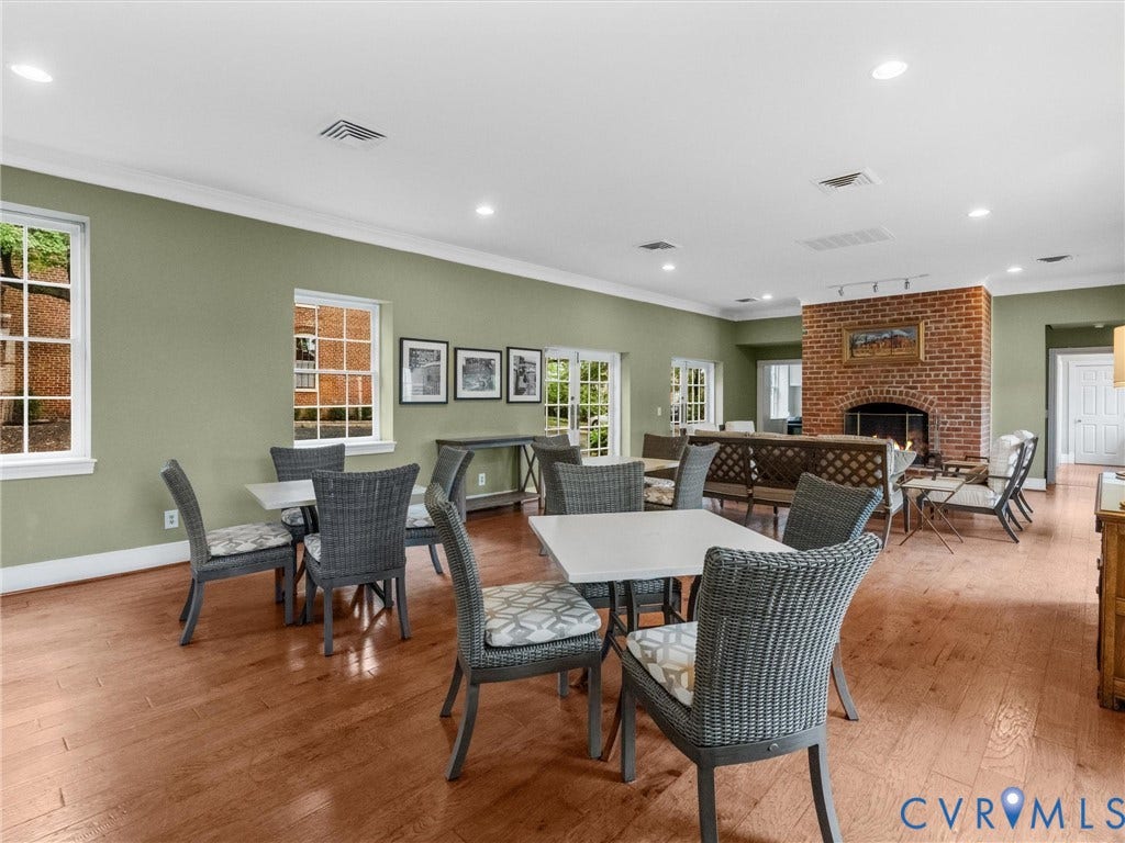 Spacious room featuring wood flooring, multiple windows, recessed lighting, and a brick fireplace
