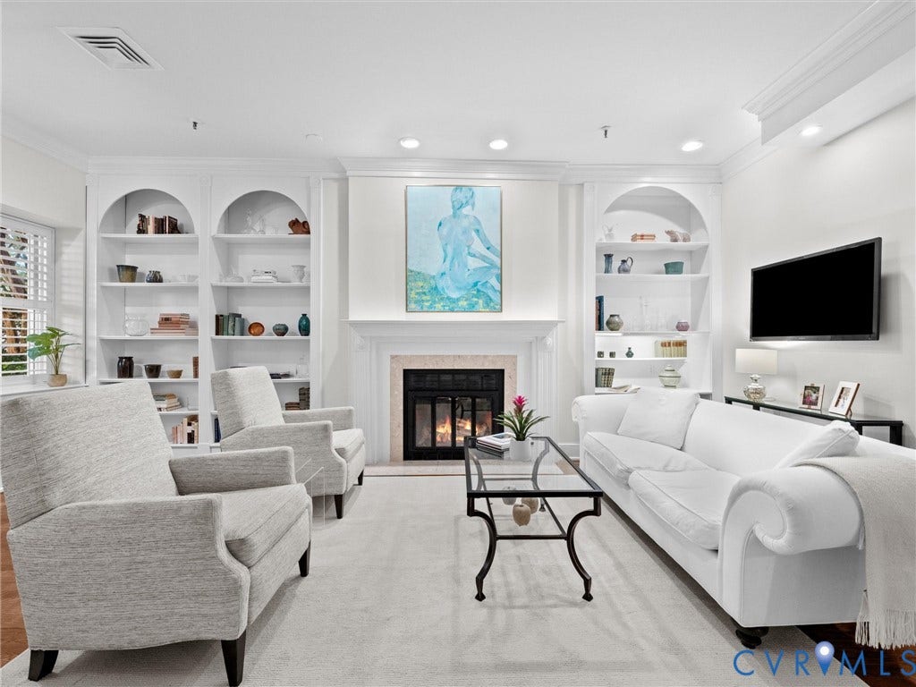 Fireplace with stone surround, two arched built-in shelving units, crown molding, and recessed lighting
