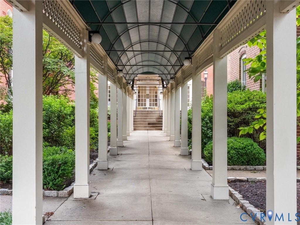 Covered walkway with a slatted lattice design, arched translucent roofing, and uniform overhead lighting