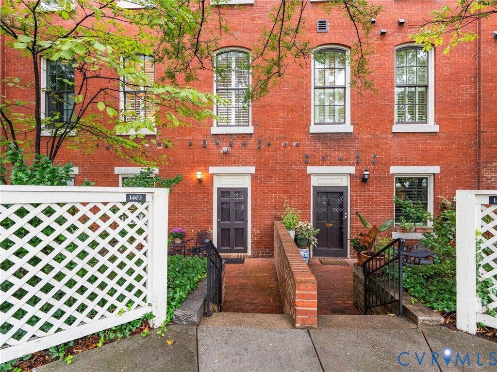Brick exterior featuring arched windows, white trim, and a private entry with a brick walkway