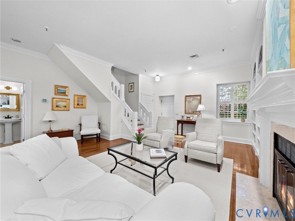 Hardwood flooring, white painted staircase with wood banister, built-in shelving, fireplace with hearth, and recessed lighting