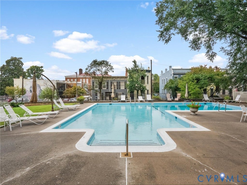 Expansive outdoor swimming pool with integrated steps, surrounded by a concrete deck and mature landscaping
