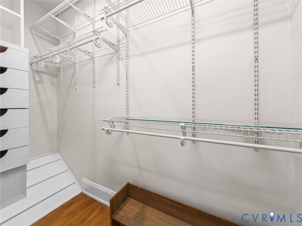 Hardwood-style flooring, white built-in drawers, wire shelving system, hanging rod, and glass shelf