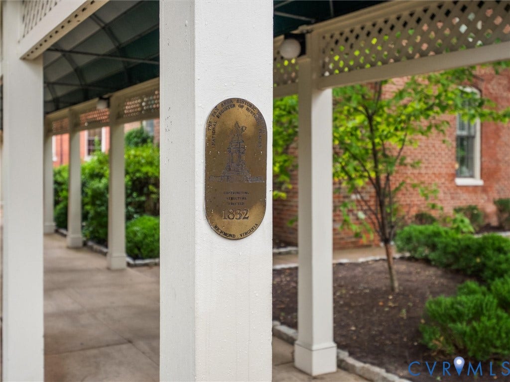 Columned walkway featuring a lattice overhead and a bronze historic plaque
