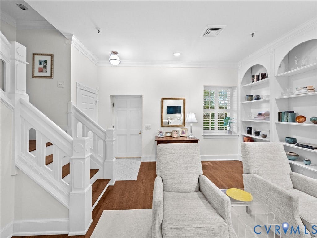 Hardwood flooring, painted white staircase, white paneled doors, built-in shelving, window with plantation shutters