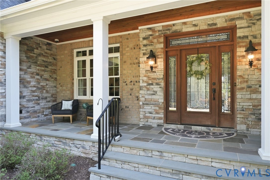 Welcoming front entrance with decorative glass doors, columns, and a covered porch