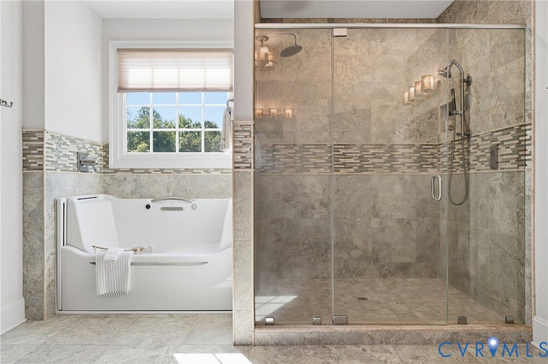 Spa-inspired bathroom with a jetted tub, tiled shower with glass door, and perfectly positioned window.