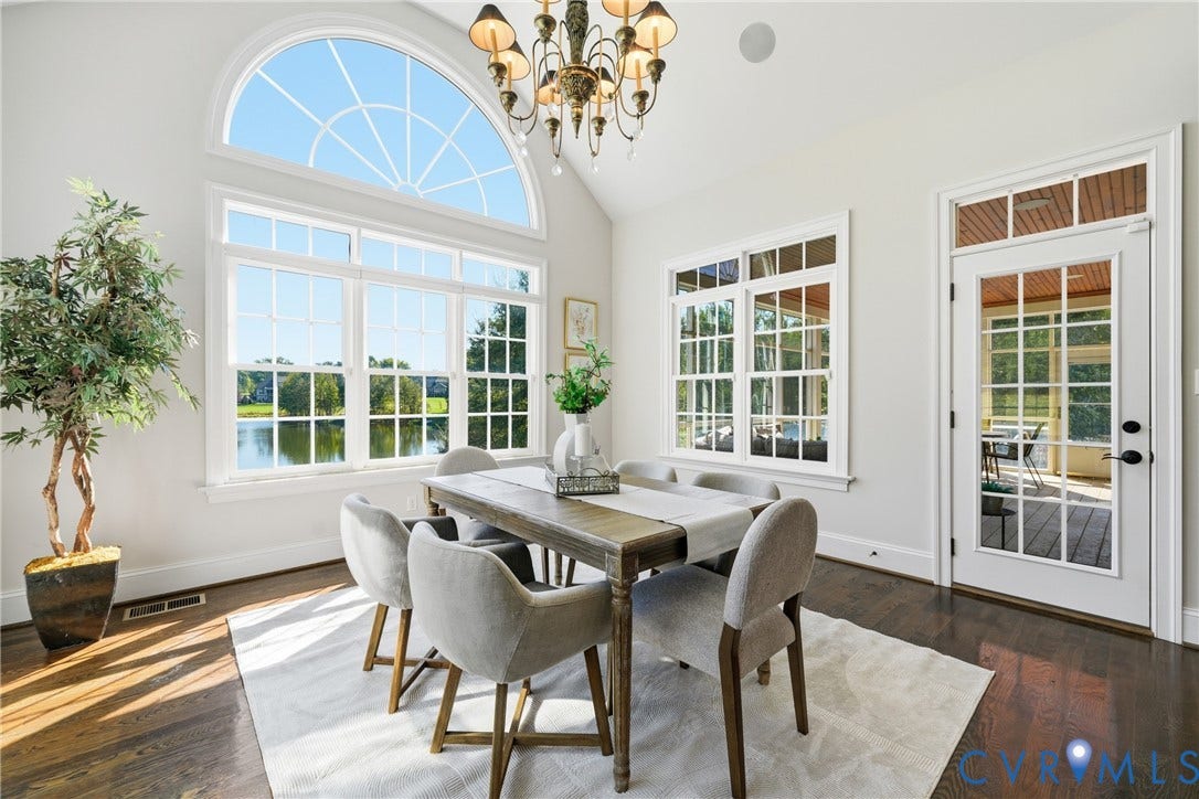 Sunlit morning room with an elegant arched window, chandelier, and waterfront views