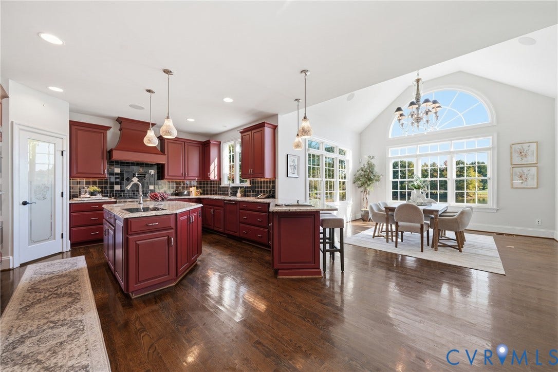 Chef-inspired kitchen with a large island, paneled and stainless steel appliances, and natural light from surrounding windows.