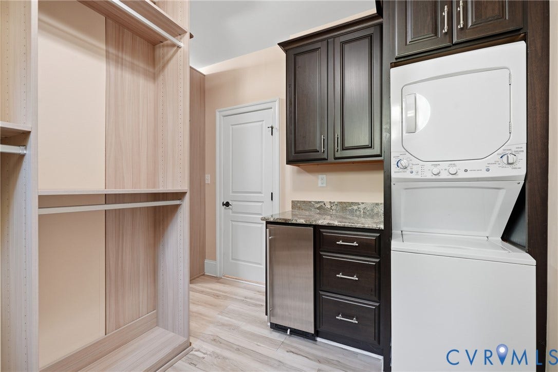 Custom walk-in wardrobe with hanging space, shelving, in-closet secondary laundry area, and built-in mini fridge