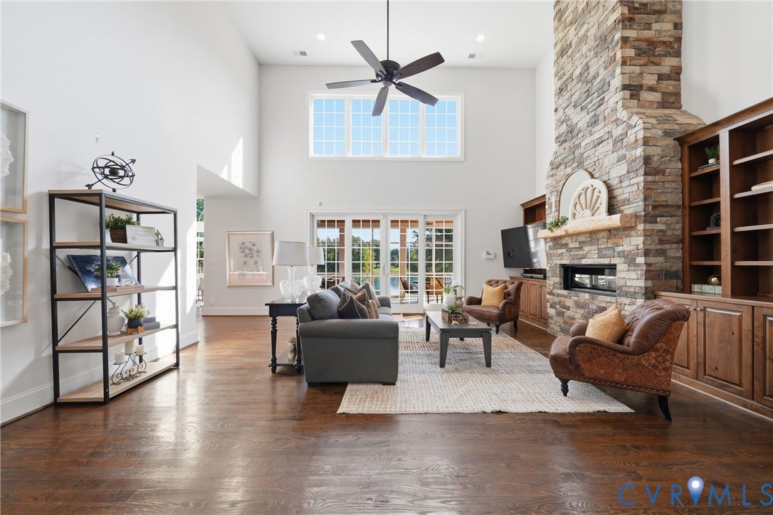 Living room with a dramatic stone fireplace, custom built-in shelving, and abundant natural light