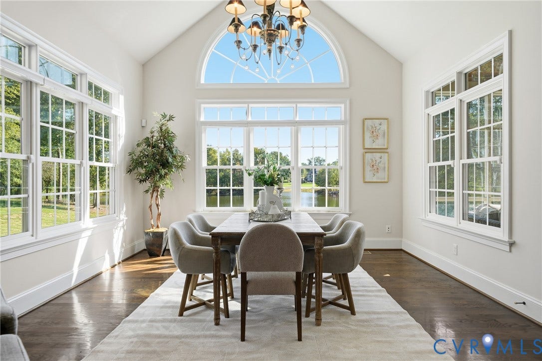 Light-filled morning room with a dramatic arched window and views of the pond and surrounding greenery.