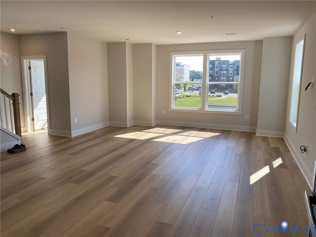 2701 St Elias Drive, #B, Richmond, VA 23294 Spacious room featuring wood-finish flooring, recessed lighting, large windows, and a built-in staircase with wood railing