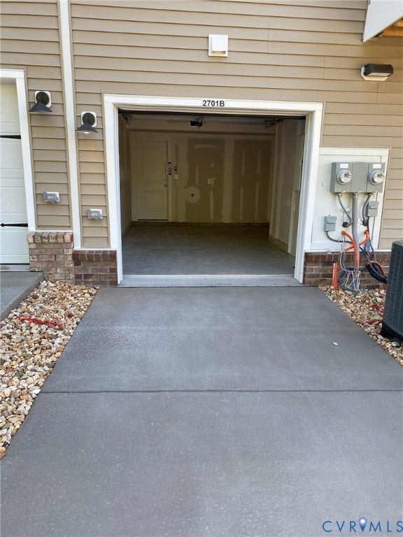 2701 St Elias Drive, #B, Richmond, VA 23294 Attached single-car garage with a concrete floor, complemented by exterior siding and brick detailing, and a concrete driveway